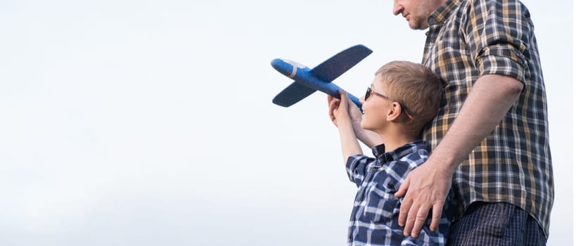 Father and son having fun in the field playing with an airplane. Father's day concept.