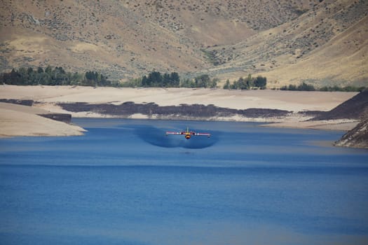 A firefighting airplane skims a Lucky Peak Reservoir surrounded by rugged hills