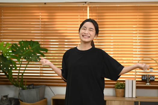 Happy teenage asian girl having fun dancing at home.