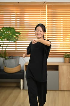 Cheerful young woman enjoying dance practice in living room.