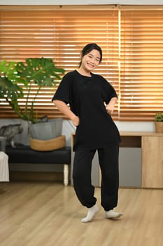 Cheerful young woman enjoying dance practice in living room.