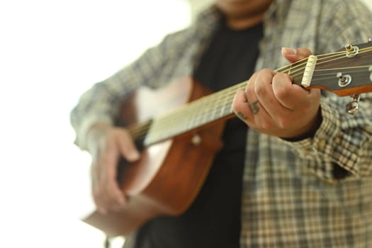Close up of man practicing acoustic guitar chords. Leisure activity and hobby concept.