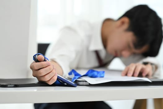 Exhausted office worker falling asleep on his desk. Fatigue in the workplace concept.
