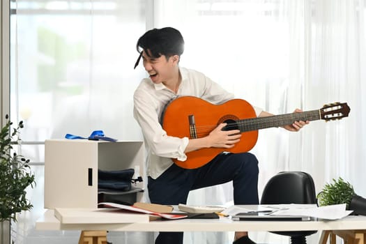 Energetic employee in white shirt with necktie around his head enjoying a music break amidst busy workday.
