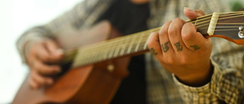 Close up of man practicing acoustic guitar chords. Leisure activity and hobby concept.