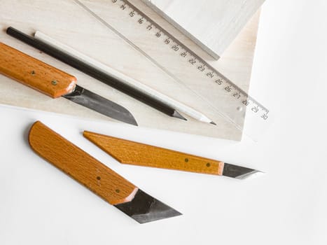 Crafting essentials. Precision knives, ruler, and pencil on wooden surface.