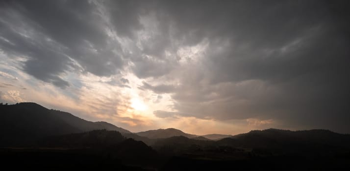 A captivating sunrise over a mountainous landscape with dramatic clouds. The scene evokes serenity and awe, highlighting the beauty of nature's interaction with light and shadow.