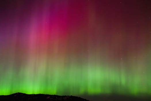 Spectacular aurora borealis illuminating the night sky with vibrant colors. This natural wonder showcases the beauty of the universe with stunning hues of green and red.