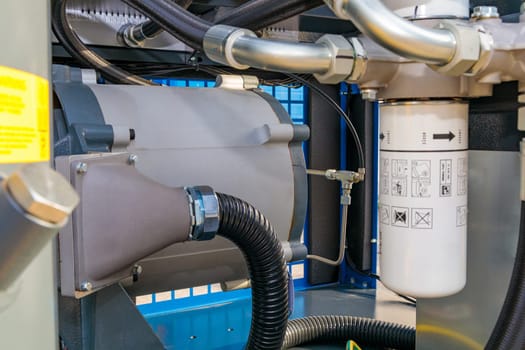 Close-up view of an industrial air compressor, highlighting its internal components, including pipes, filters, and other mechanical parts
