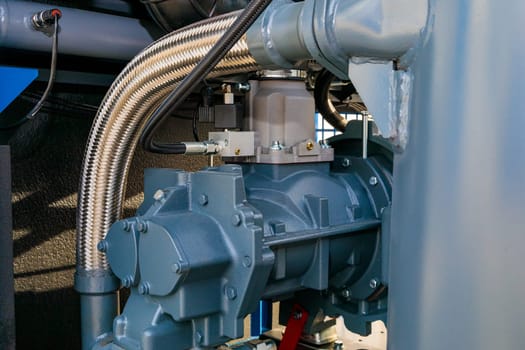 Close-up of a screw compressor with a flexible metal hose, showcasing its components and industrial application