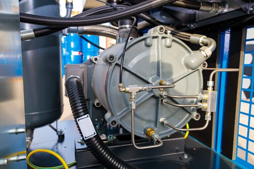 Close-up of an industrial air compressor featuring connecting pipes, hoses, and valves
