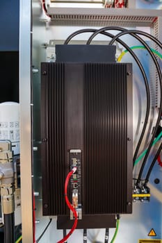 Electronic frequency converter with cooling fins and cables, mounted inside an electrical cabinet