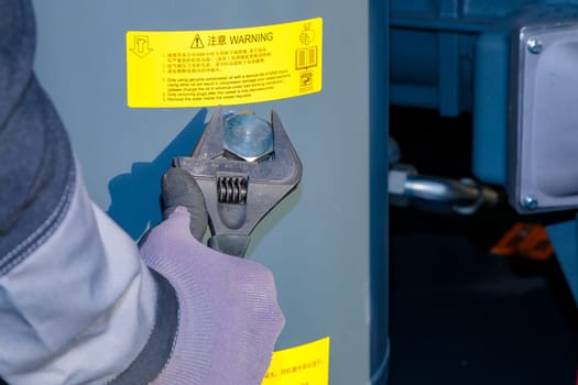 Technician is filling oil into industrial compressor using an adjustable wrench.