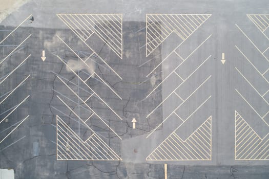 Top-down aerial view of an empty parking lot with clearly marked lines and directional arrows. Ideal for concepts relating to urban planning, organization, and space.