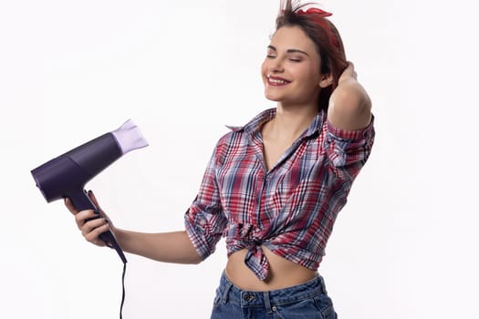 A cheerful young woman is happily drying her hair with a stylish hairdryer, radiating both confidence and joy