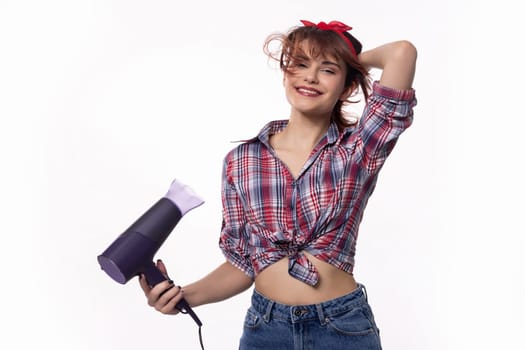 A cheerful young woman playfully poses with a hairdryer, showcasing her trendy style and fashion sense