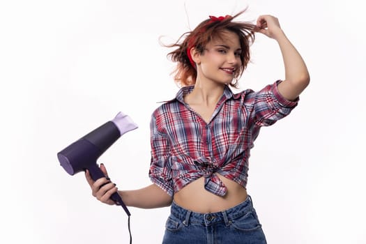 A playful young woman joyfully uses a hair dryer, delighting in her hairstyle with vibrant energy and enthusiasm