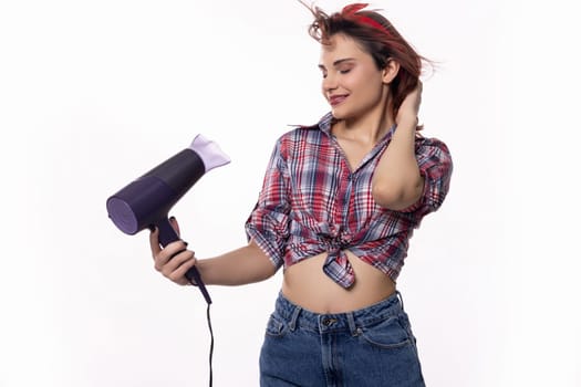 A stylish young woman is happily using a blow dryer to expertly style her beautiful hair, showcasing a trendy look
