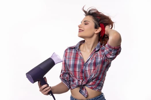 A trendy female model is playfully using a hair dryer in a stylish and vibrant indoor setting filled with elegance