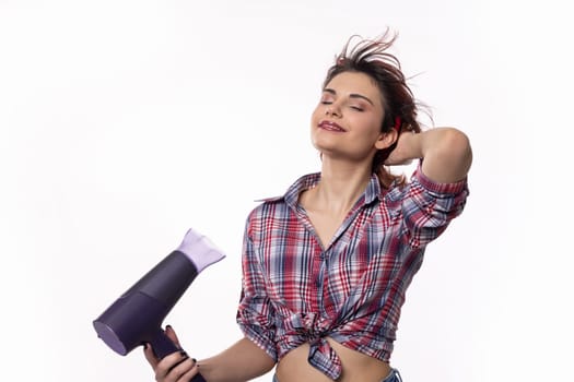 A confident woman is joyfully enjoying the process of styling her hair with a vibrant purple hair dryer