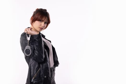 A selfassured young woman confidently holds stylish handcuffs, showcasing empowerment and flair in her chic outfit