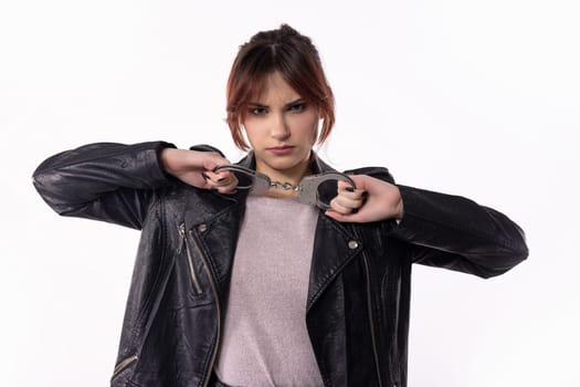A confident young woman striking a fashionable pose in a black leather jacket, showcasing modern style.