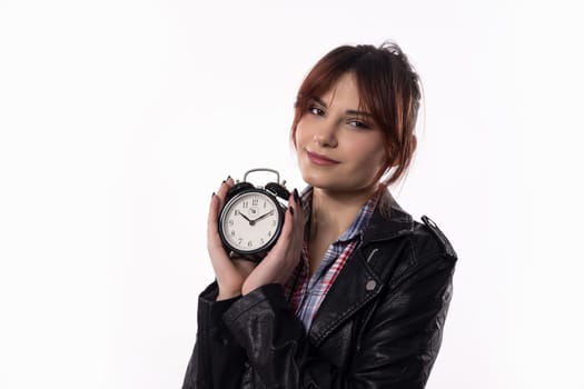 A confident young woman strikes a pose with a slim alarm clock, showcasing her very stylish look and readiness