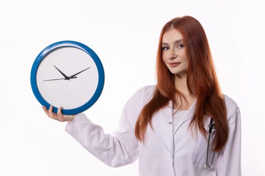 A female healthcare worker in a lab coat holding a clock, symbolizing time management in healthcare.