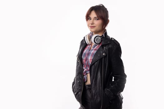 A trendy and fashionable young woman poses with confidence, wearing a stylish leather jacket and trendy headphones