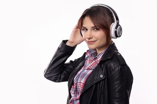 A stylish young woman joyfully listens to music, showcasing modern headphones and an outfit that reflects her vibe