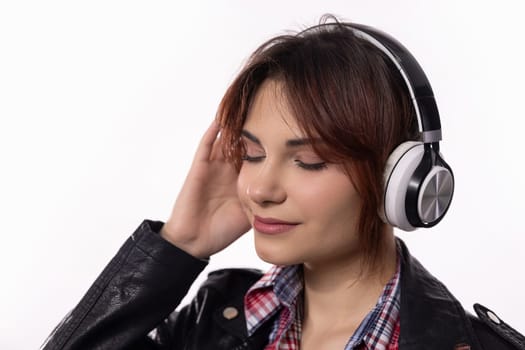 A young woman wearing stylish headphones is fully immersed in enjoying her music, radiating pure bliss and tranquility