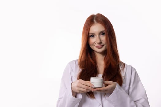 A cheerful young woman proudly showcases a skincare product in a beautifully bright, modern environment