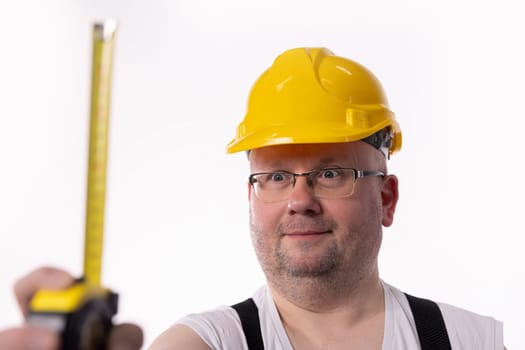 A construction worker confidently holds a measuring tape while showcasing his essential and impressive safety gear