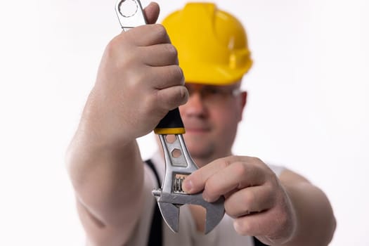 A dedicated and focused construction worker wearing a hard hat firmly grips a wrench, prepared for the job ahead