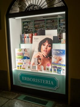 Cremona, Lombardy, Italy October 15th 2024 An illuminated herbalist shop window showcasing various beauty and wellness products, creating an alluring display for passersby at night