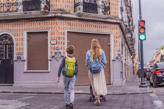 Mother tourist with her toddler and teenage sons walking through the colorful colonial streets of Puebla, Mexico. Travel, cultural exploration, and vibrant architecture concept.