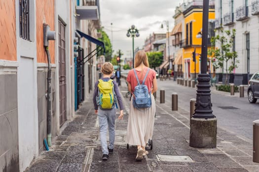 Mother tourist with her toddler and teenage sons walking through the colorful colonial streets of Puebla, Mexico. Travel, cultural exploration, and vibrant architecture concept.