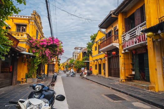 Old town street in Hoi An city with traditional ancient yellow houses and buildings in historical Asian style in summer in day. Hoi An, Vietnam - September 12, 2024