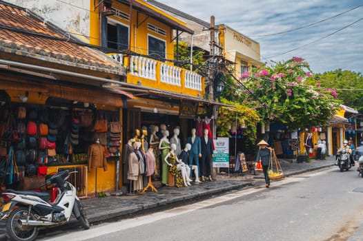 Old town street in Hoi An city with traditional ancient yellow houses and buildings in historical Asian style in summer in day. Hoi An, Vietnam - September 12, 2024