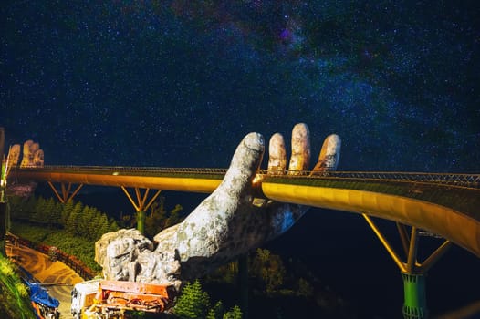 Golden Bridge in Ba Na Hills entertainment park in Da Nang in Vietnam on the mountain at night under the starry sky