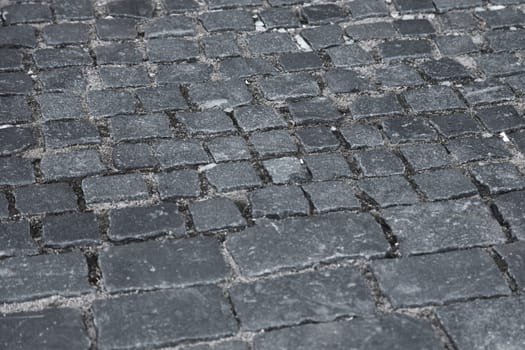 Fragment of an old road paved with gray stones, view from above.