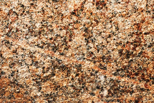 Brown stone wall close up. Granite texture. Natural red granite with a grainy pattern. Stone background. Solid rough surface of rock.