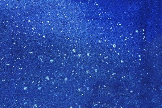 The surface of an old, spotted, uneven stone wall painted blue.
