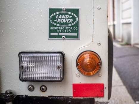 Cremona, Lombardy, Italy October 15th 2024 Detail of rear light and historic italian registry badge on classic white land rover defender, parked on urban street