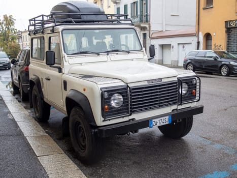 Cremona, Lombardy, Italy October 15th 2024 Classic white land rover defender 110 suv equipped with roof rack and cargo box parked on a city side street