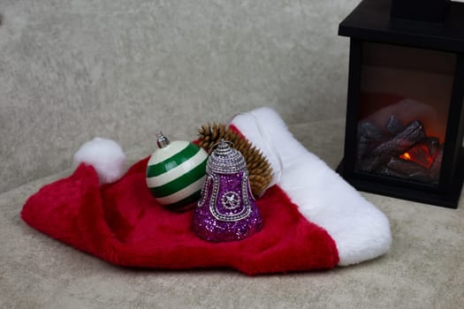 Christmas tree toys lie on red cap, symbols of the New Year, creating festive mood by decorating house with toys for New Year, New Year and Christmas celebration concept