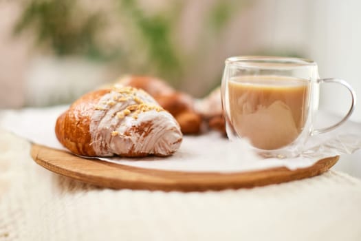 Delicious fresh french croissants and glass of coffee on wooden tray for breakfast in bed in the morning, tasty breakfast