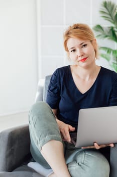 Woman working on laptop online on sofa