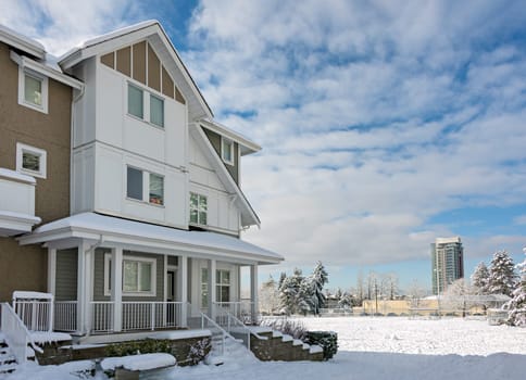 Residential townhouses and high-rise building on bright winter day with cloudy sky background.