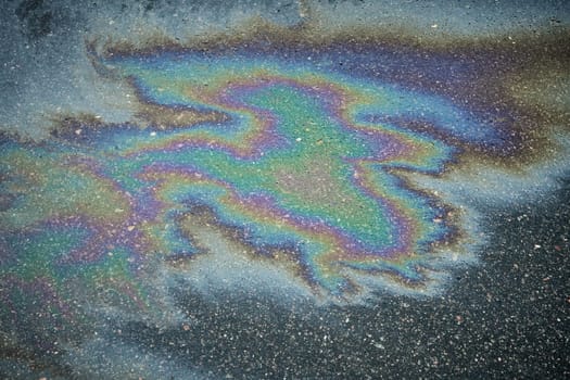 Close-up of a Glimmering Oil or Gas Spill on Rain-soaked Tarmac, Viewed from Above